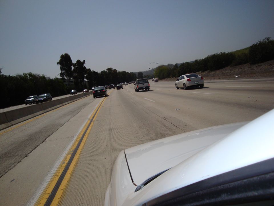White car's hood and windshield on a sunny highway with other vehicles