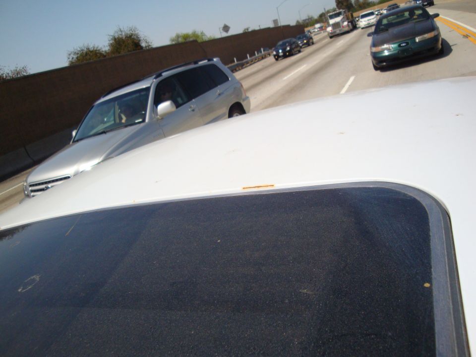 Green 1995 Ford Taurus sedan driving on a highway, front view