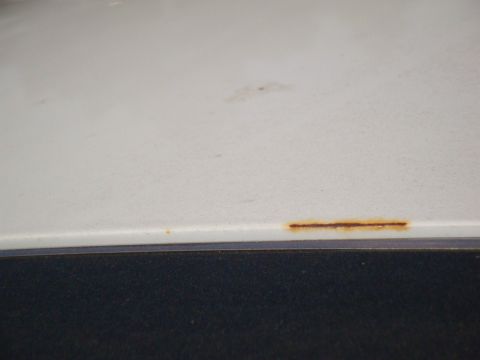 1995 Ford Taurus - Close-up of a white car panel showing a small rust spot near the bottom edge.