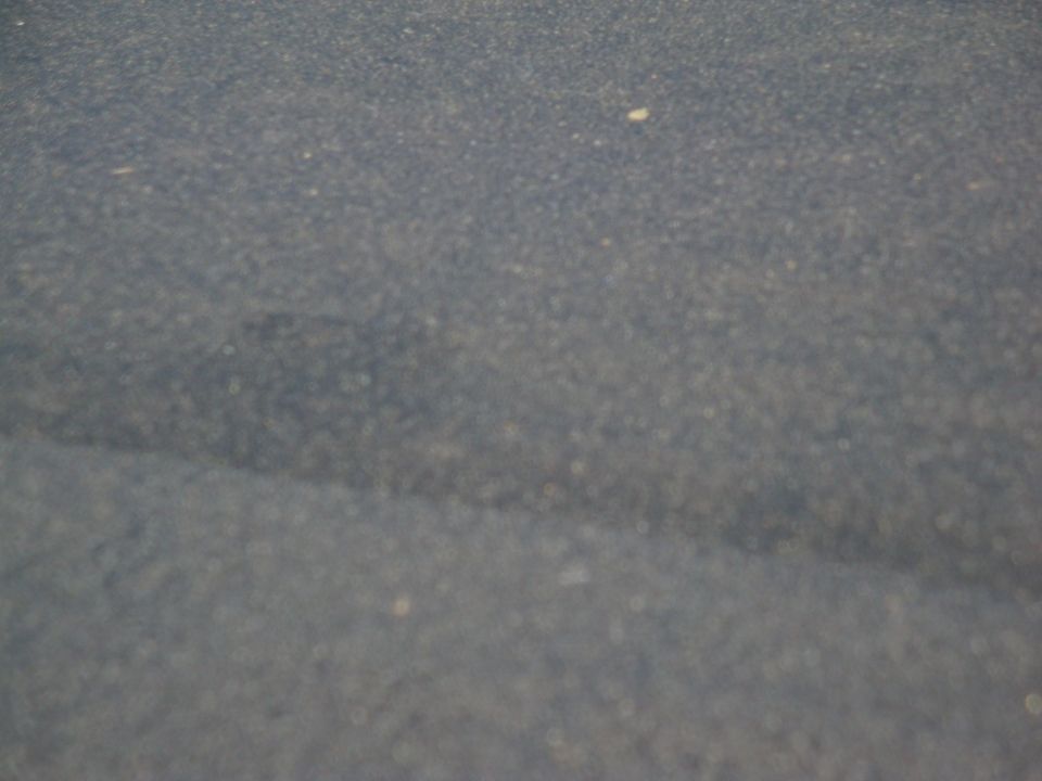 Close-up of a dark gray car hood with some dust specks