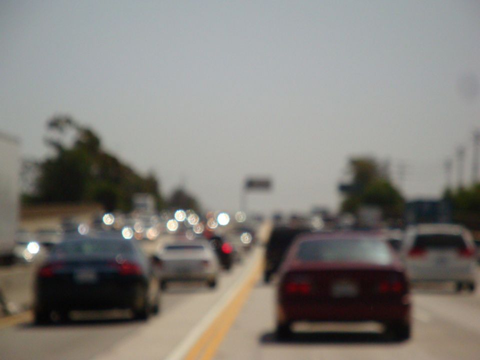 Traffic jam on a highway with multiple cars visible, including a dark sedan in the foreground