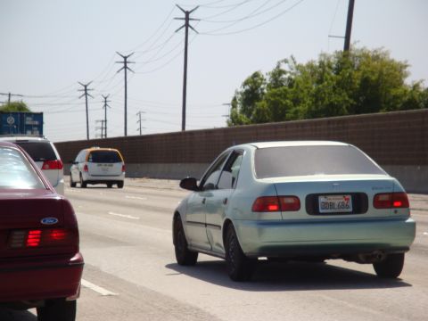1995 Ford Taurus - A light blue 1995 Honda Civic sedan is seen from the rear on a highway, with other vehicles nearby.