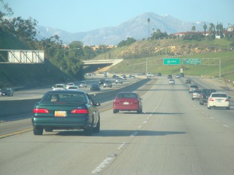 1995 Ford Taurus - A green 1995 Ford Taurus sedan is seen from behind on a multi-lane highway with other vehicles.