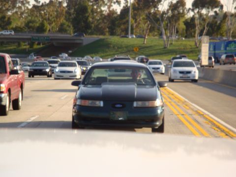 1995 Ford Taurus - A dark green 1995 Ford Taurus is seen driving on a busy highway during the day.