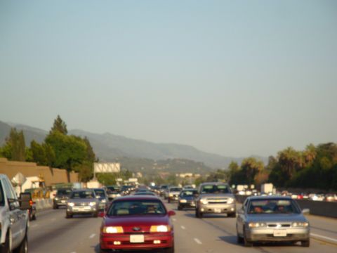 1995 Ford Taurus - Multiple vehicles are stuck in a traffic jam on a highway with mountains visible in the background.