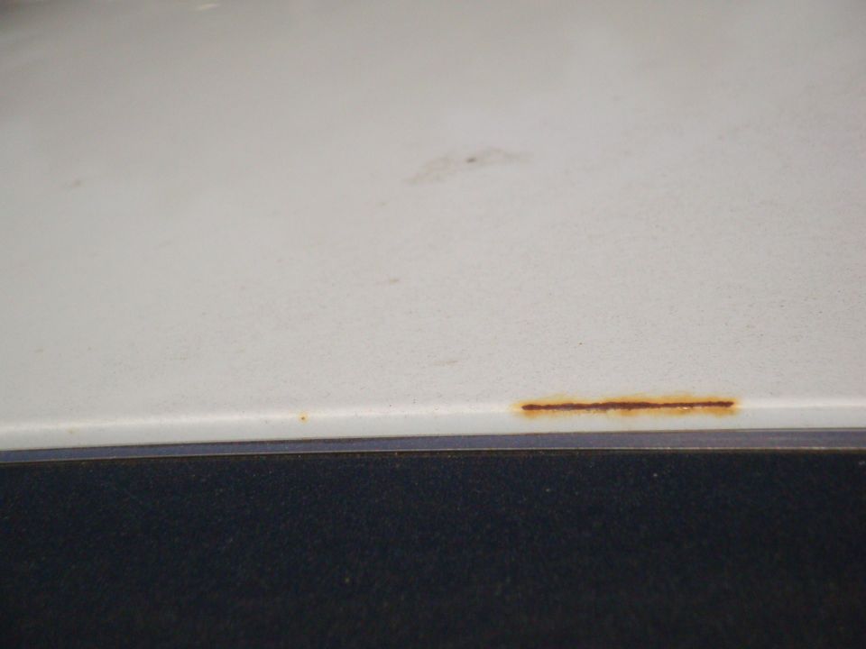 White car panel with a line of rust along the bottom edge