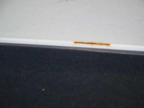 1995 Ford Taurus - Close-up of rust forming on the lower edge of a white car door.