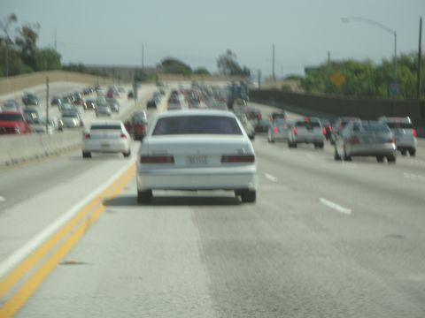 1995 Ford Taurus - A white 1995 Ford Taurus sedan travels down a busy highway.