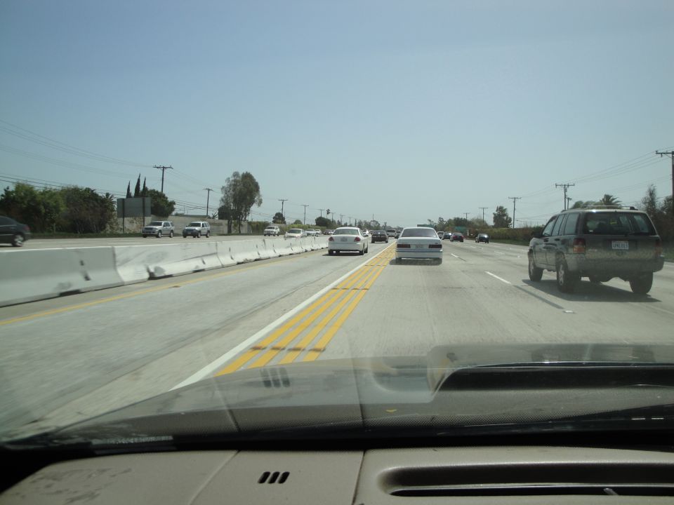 Driving on a sunny day on a highway with multiple cars ahead and to the right