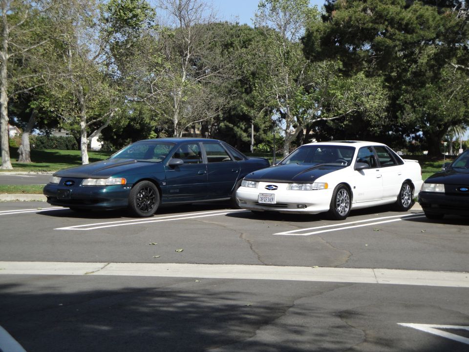 Dark green sedan with black hood and wheels parked in a lot