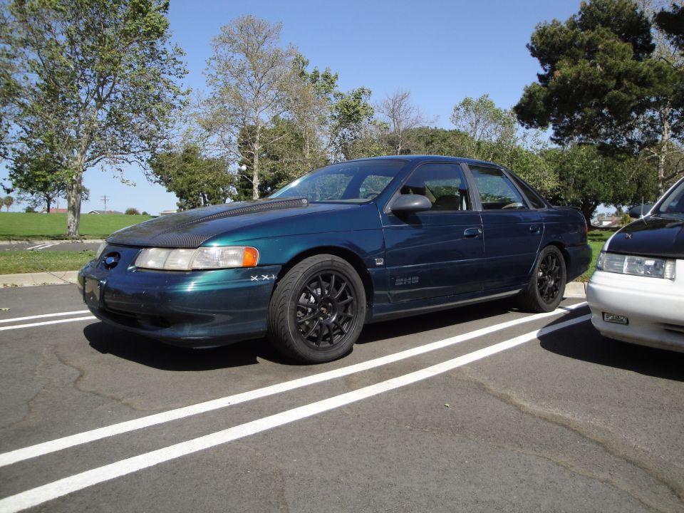Dark blue sedan with black rims parked in a lot. Another car is next to it