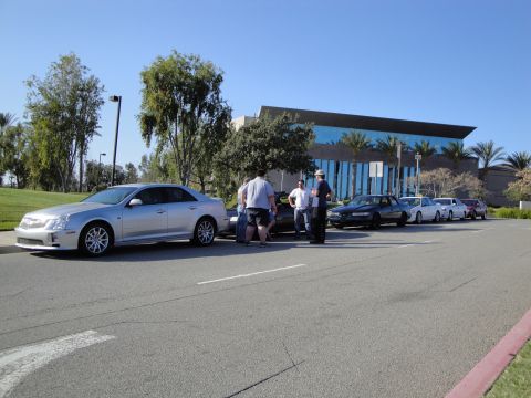 1995 Ford Taurus - Several cars are parked in a line on a sunny day with a modern building in the background.