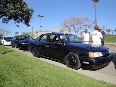1995 Ford Taurus - A line of sedans parked on a sunny day, with the closest car being a black 1995 Ford Taurus.