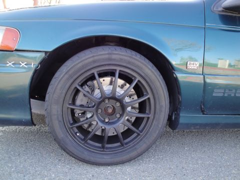 1995 Ford Taurus - A close-up view of a car's wheel, showing the tire, rim, and brake rotor, along with a portion of the fender and door.