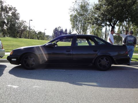1995 Ford Taurus - Side profile of a black 1995 Ford Taurus sedan parked on asphalt.