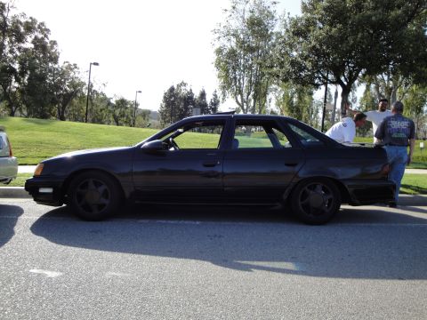 1995 Ford Taurus - Side profile of a black 1995 Ford Taurus sedan parked outdoors.