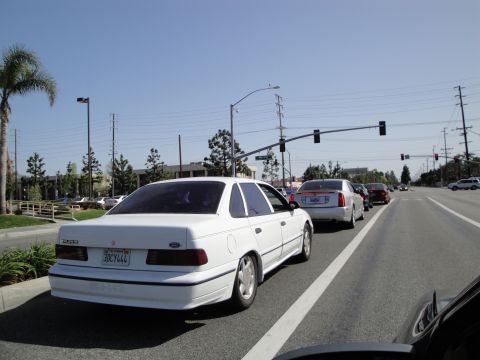 1995 Ford Taurus - White 1995 Ford Taurus sedan driving in traffic on a sunny day.
