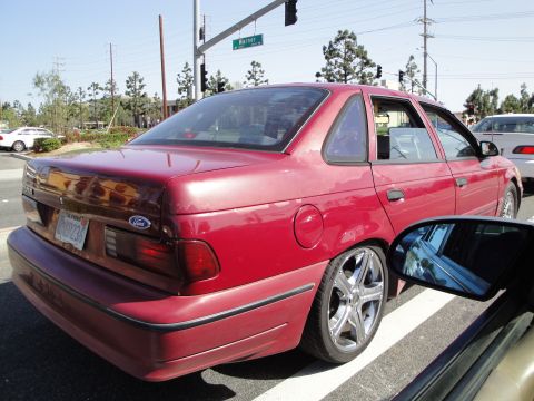 1995 Ford Taurus - Rear view of a red 1995 Ford Taurus sedan at a street intersection.