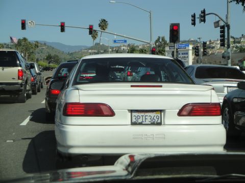 1995 Ford Taurus - White 1995 Ford Taurus in traffic on a sunny day, with other cars visible.