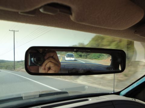 1995 Ford Taurus - Reflection in the rearview mirror shows a white sedan ahead on the road.