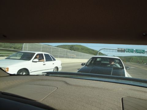 1995 Ford Taurus - A white 1995 Ford Taurus sedan is seen from inside another vehicle on a highway.