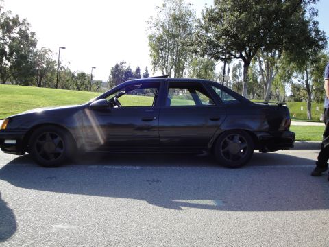 1995 Ford Taurus - A black 1995 Ford Taurus sedan is parked outdoors on a sunny day.