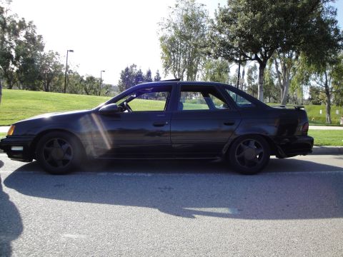 1995 Ford Taurus - Side profile of a black 1995 Ford Taurus sedan parked on asphalt.