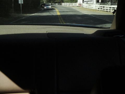 1995 Ford Taurus - A 1995 Ford Taurus is seen driving on a two-lane road with a white fence lining the side.