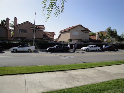 1995 Ford Taurus - Several cars are parked along a residential street under a clear blue sky.