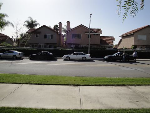 1995 Ford Taurus - Several cars are parked along a suburban street in front of houses.