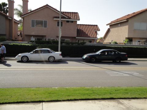 1995 Ford Taurus - Two sedans are parked on the side of a street in front of houses.