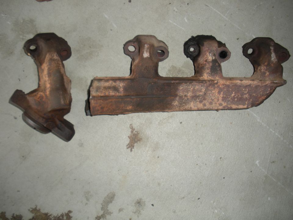 two rusty exhaust manifolds on concrete floor