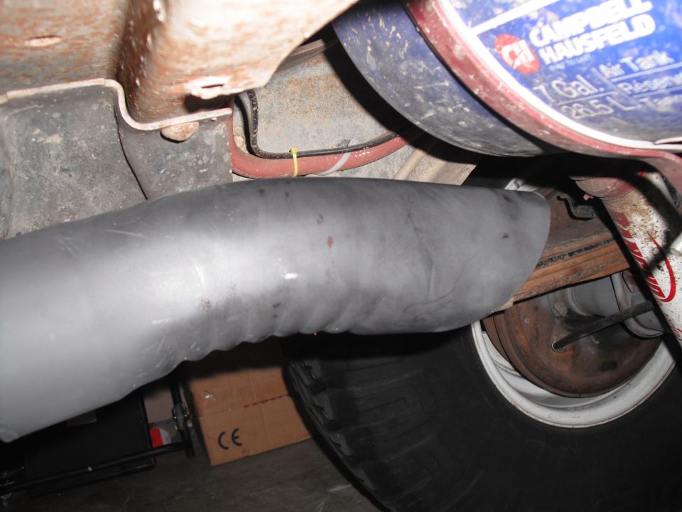 Close-up of a vehicle's undercarriage showing a gray exhaust pipe and a blue Campbell Hausfeld air tank