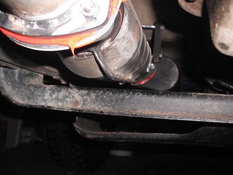 1991 Ford Bronco - The underside of a vehicle shows a close-up view of a custom exhaust pipe connection with red sealant.
