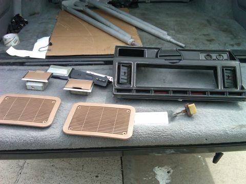 1986 Ford Bronco - Various car interior parts, including dashboard trim and vent covers, are displayed on a textured surface.