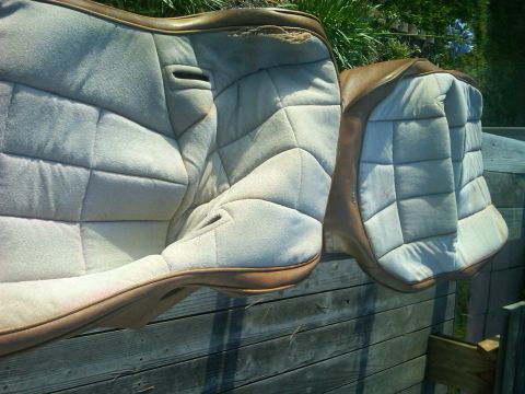 1986 Ford Bronco - Quilted car seats with brown trim are shown outdoors, resting on a wooden surface.