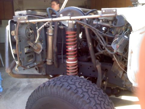 1986 Ford Bronco - The front tire and engine bay of a white vehicle are visible, with many components removed.