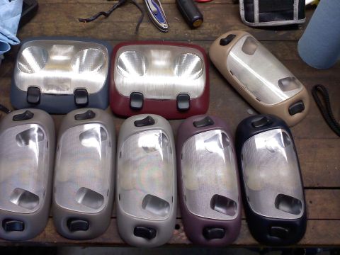 1992 Ford Bronco - Several interior dome lights are laid out on a wooden surface, showing different colors and designs.