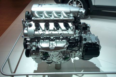 1997 Ford Taurus - A V8 engine is displayed on a stand, with a portion of a white vehicle visible behind it.