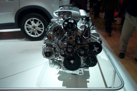 1997 Ford Taurus - A highly polished V8 engine is displayed, its intricate belt and gear system, positioned beside the wheel of a silver car.