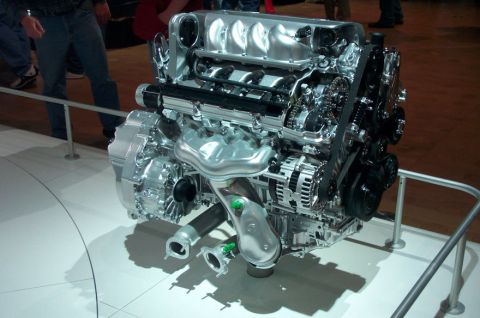 1997 Ford Taurus - A cutaway V8 engine and transaxle assembly displayed on a white turntable behind a chrome rail at an auto show, sectioned to expose the tim…
