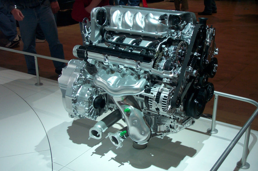 Cutaway V8 engine and transaxle on a white auto show display stand