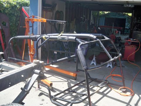 1985 Ford Bronco - Custom roll cage assembly attached to a vehicle frame in a garage setting.