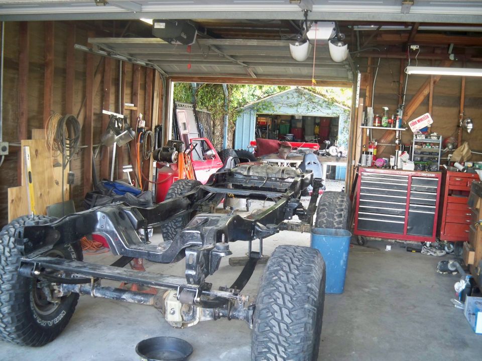 Vehicle frame and chassis with large tires on jack stands in a garage