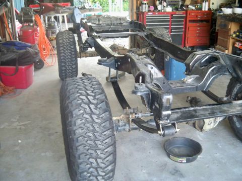 1985 Ford Bronco - The chassis and suspension components of a vehicle are visible, along with large off-road tires.