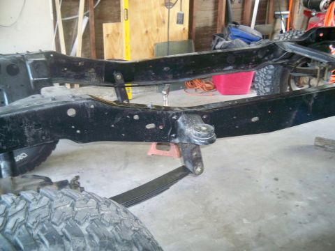 1985 Ford Bronco - Close-up of a vehicle's frame and suspension components in a garage setting.