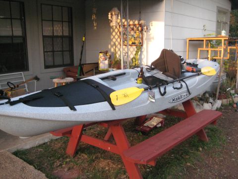 1953 Ford Mainline - A light gray kayak with a yellow paddle rests on a red picnic table, with a beer bottle nearby.
