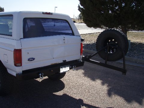 1993 Ford Bronco - Rear view of a white 1993 Ford Bronco, a swing-away spare tire carrier and aftermarket bumper.