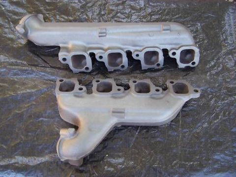 1972 Ford Ranchero - Two exhaust manifolds are laid out on a black tarp, likely for a vehicle restoration project.