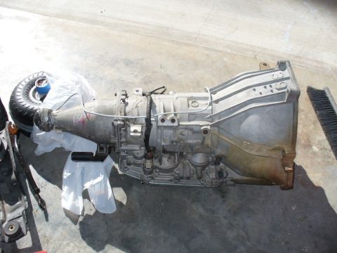 1995 Ford Thunderbird - A transmission assembly is shown lying on a concrete surface, with a tire visible at one end.